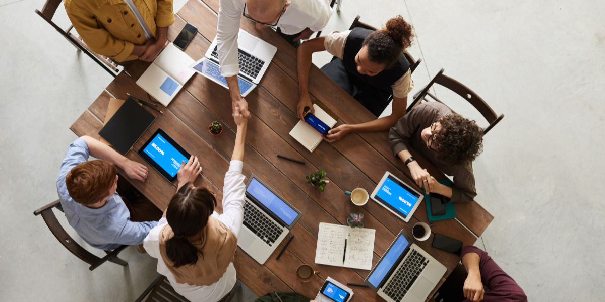 Equipo de trabajo sentados en una mesa hablando y cerrando negocios